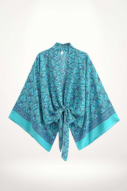 Kimono bleu vif avec motifs floraux, manches larges et ceinture nouée, sur fond neutre