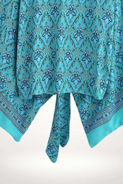 Kimono en tissu turquoise orné de motifs floraux bleus et de bordures décoratives, style boho chic