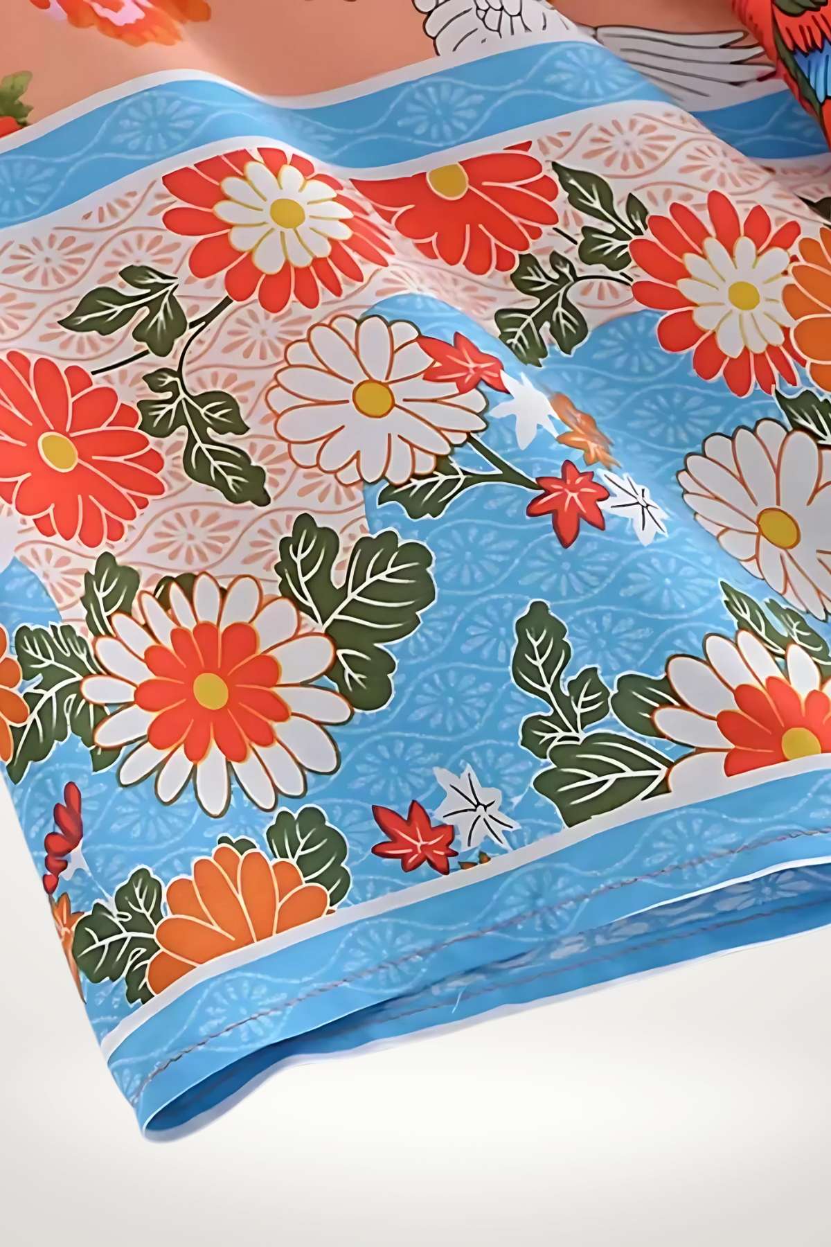 Un kimono coloré avec des motifs floraux rouges et blancs sur un fond bleu clair, évoquant la légèreté estivale