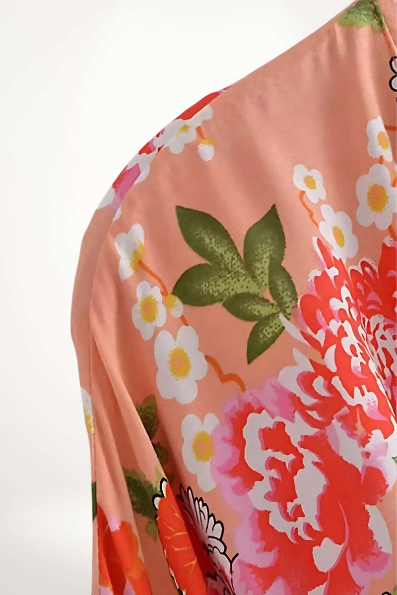 Un kimono léger aux motifs floraux colorés, dominé par des teintes roses, blanches et vertes, sous un éclairage doux
