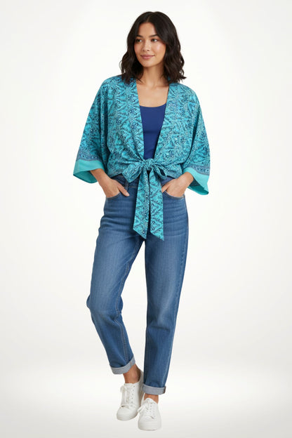 Femme portant un kimono bleu turquoise à motifs, avec un débardeur bleu et un jean décontracté