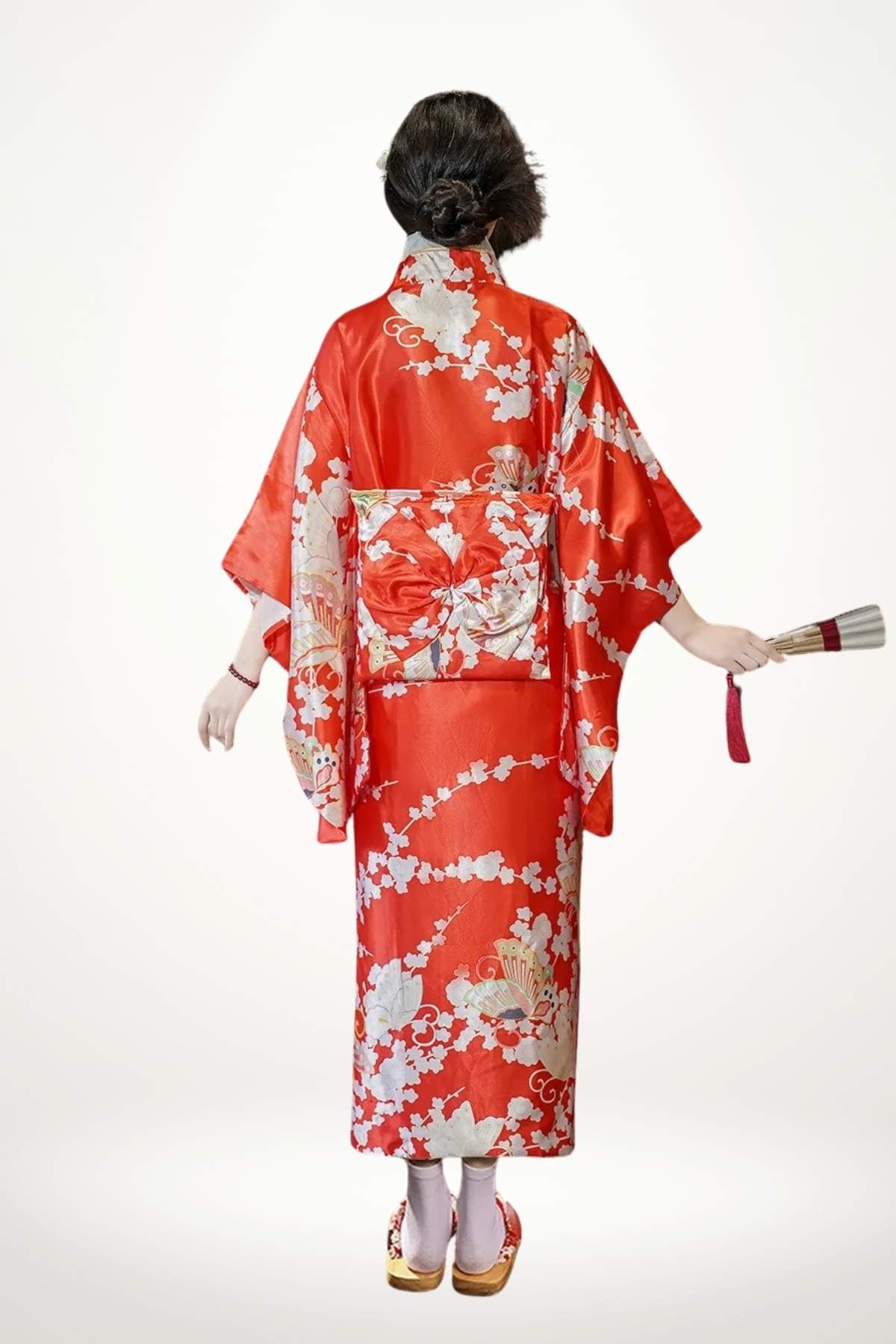 Femme en kimono rouge brillant avec motifs floraux, tenant un éventail, vue de dos sur fond clair