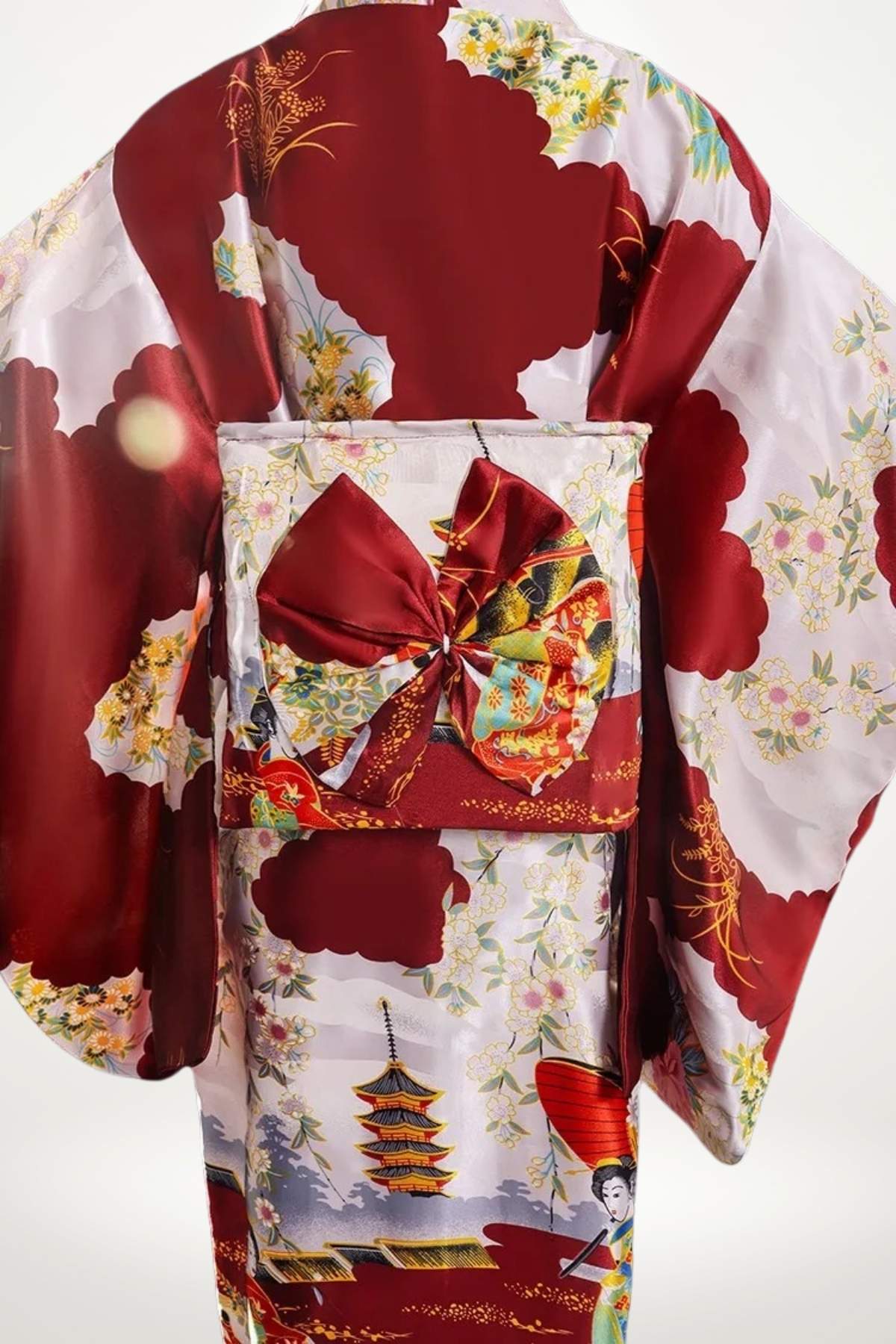 Kimono en satin rouge avec motifs floraux et pagodes, ceinturé d’un obi orné d’un nœud élégant