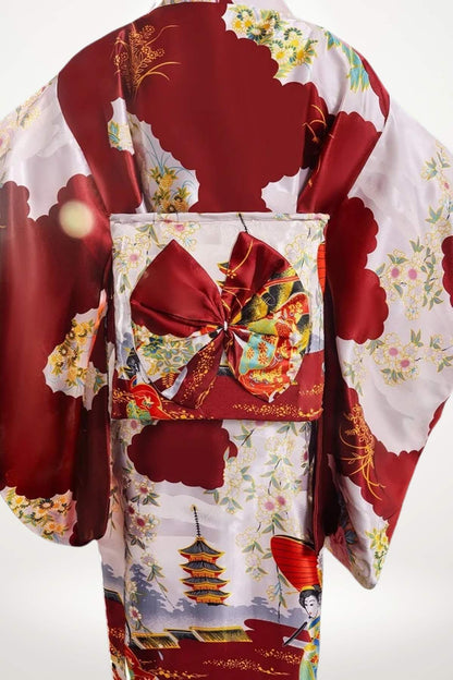 Kimono en satin rouge avec motifs floraux et pagodes, ceinturé d’un obi orné d’un nœud élégant