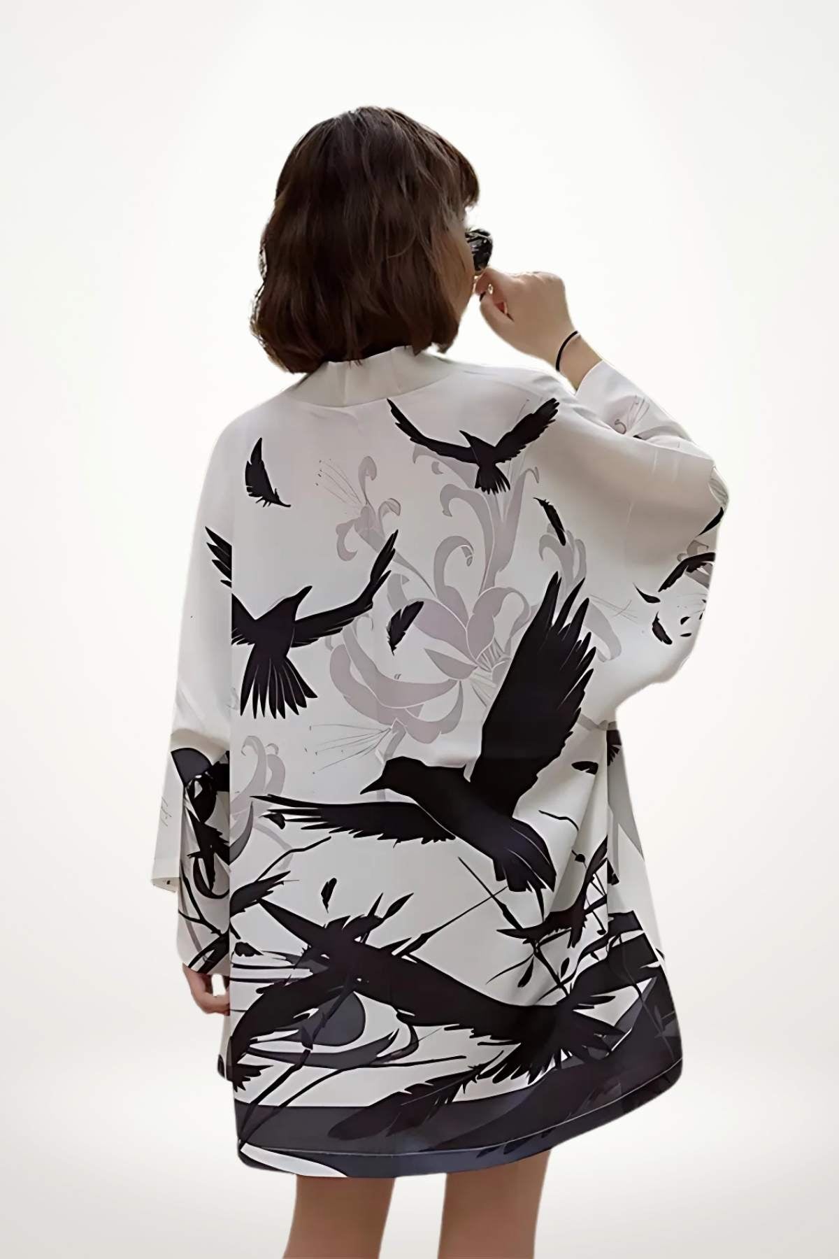 Femme de dos portant un kimono blanc avec des motifs noirs d'oiseaux sur fond clair