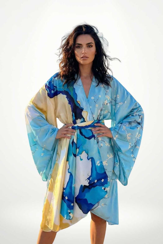 Femme portant un kimono aux couleurs bleu et jaune, avec des motifs floraux, se tenant debout dans un décor lumineux