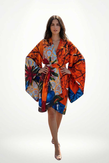 Femme portant un kimono coloré orange avec des motifs floraux, posé avec élégance sur un fond blanc