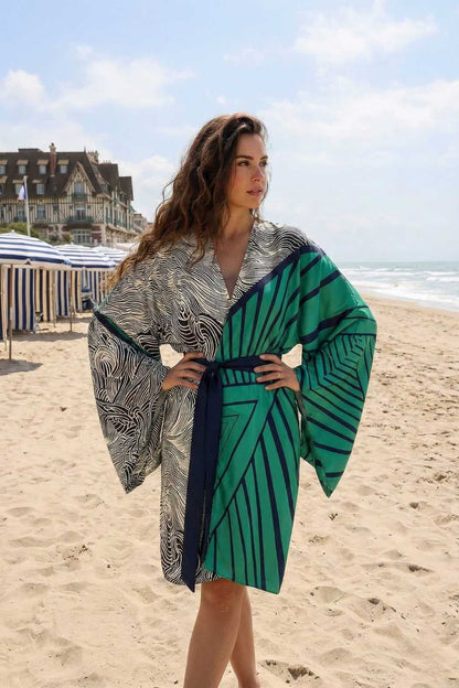 Femme portant un kimono en satin aux motifs géométriques verts et noirs, sur une plage ensoleillée