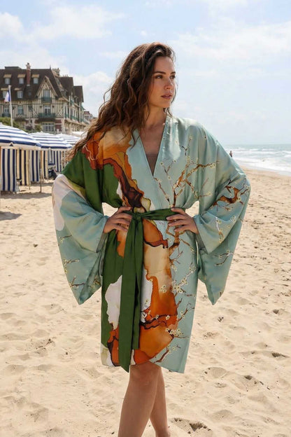 Femme portant un kimono aux motifs colorés, avec des manches larges, sur une plage ensoleillée