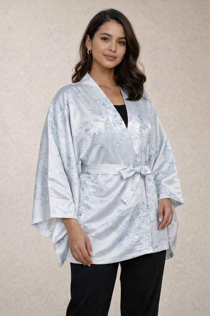 Femme portant un kimono en satin argenté avec motifs floraux, posé sur un fond neutre
