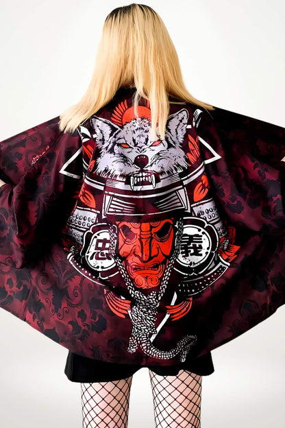 Femme vue de dos portant un kimono court noir et rouge avec des motifs de loup et de samouraï, décor