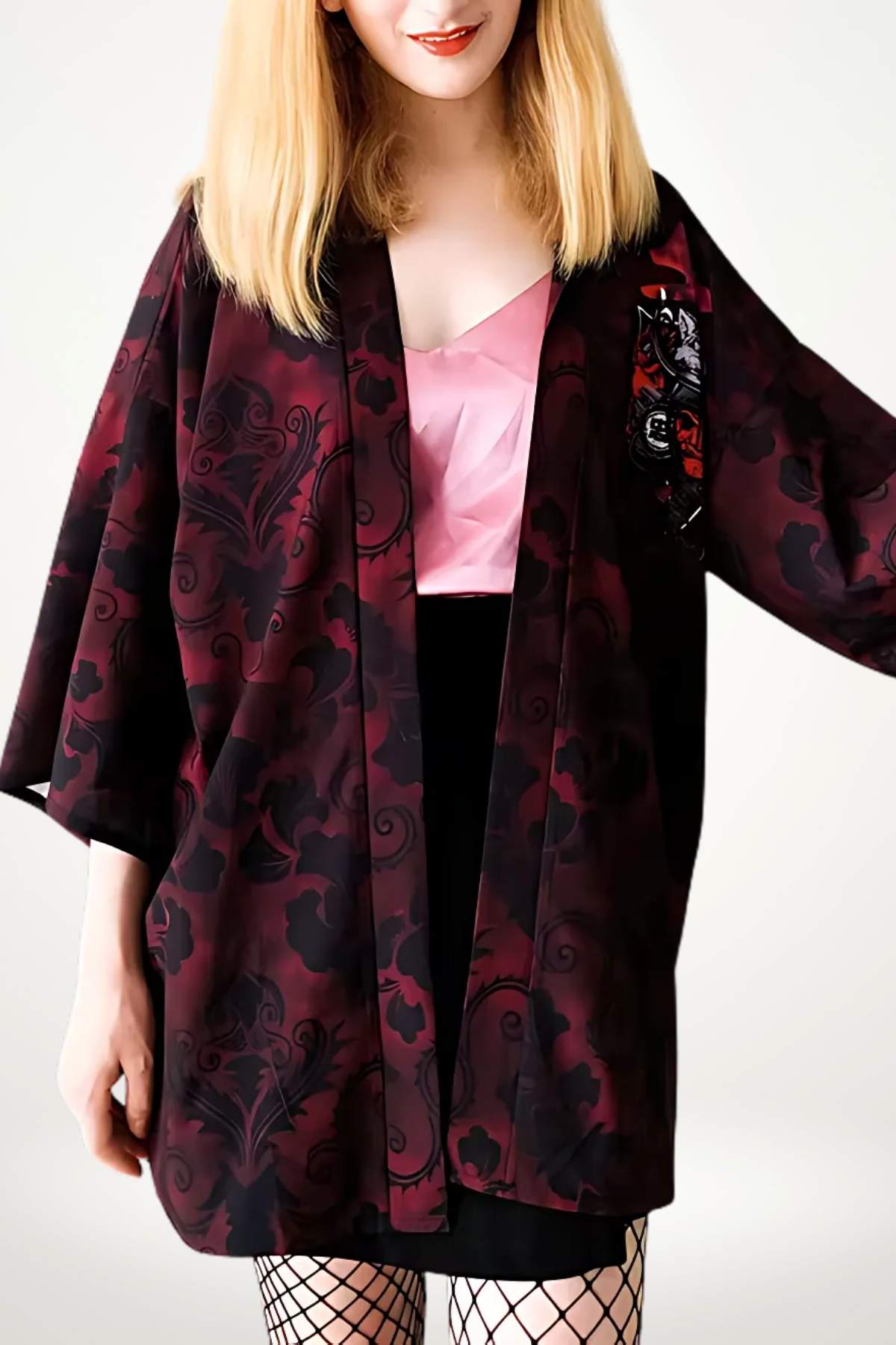 Femme portant un kimono court en velours bordeaux avec motifs floraux, sur un top rose et jupe noire