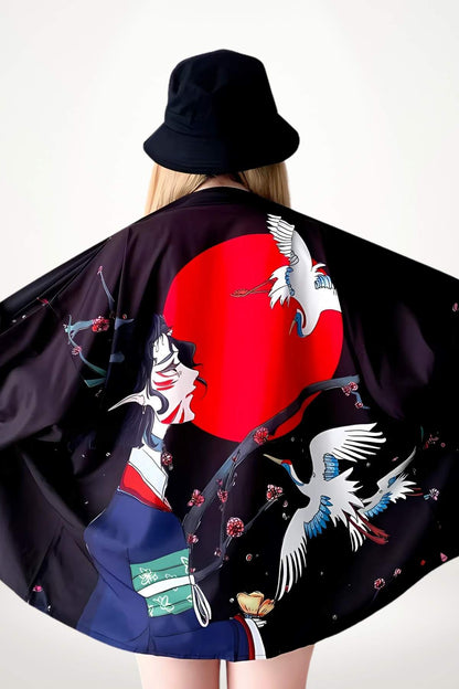 Femme portant un kimono noir orné de motifs floraux et de grues, avec un chapeau noir en arrière-plan