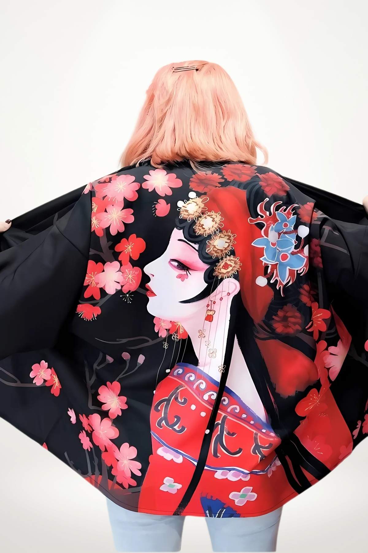 Femme portant un kimono court noir avec motifs floraux rouges et une illustration artistique au dos, dans un décor minimaliste