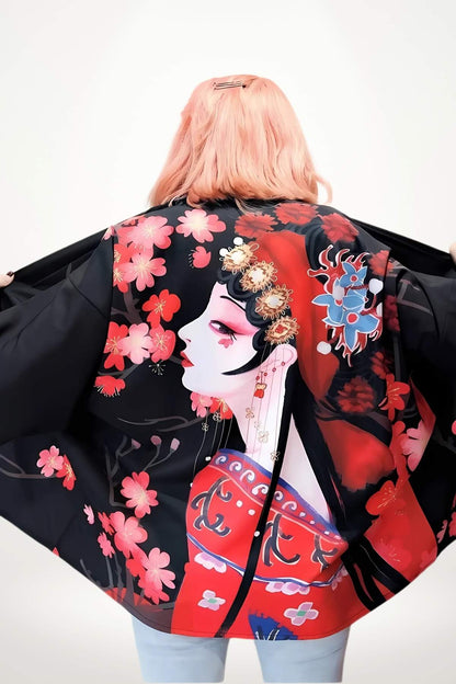 Femme portant un kimono court noir avec motifs floraux rouges et une illustration artistique au dos, dans un décor minimaliste