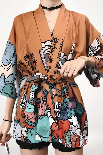 Kimono court en tissu orange avec motifs colorés et inscriptions, porté avec un short noir et des accessoires modernes