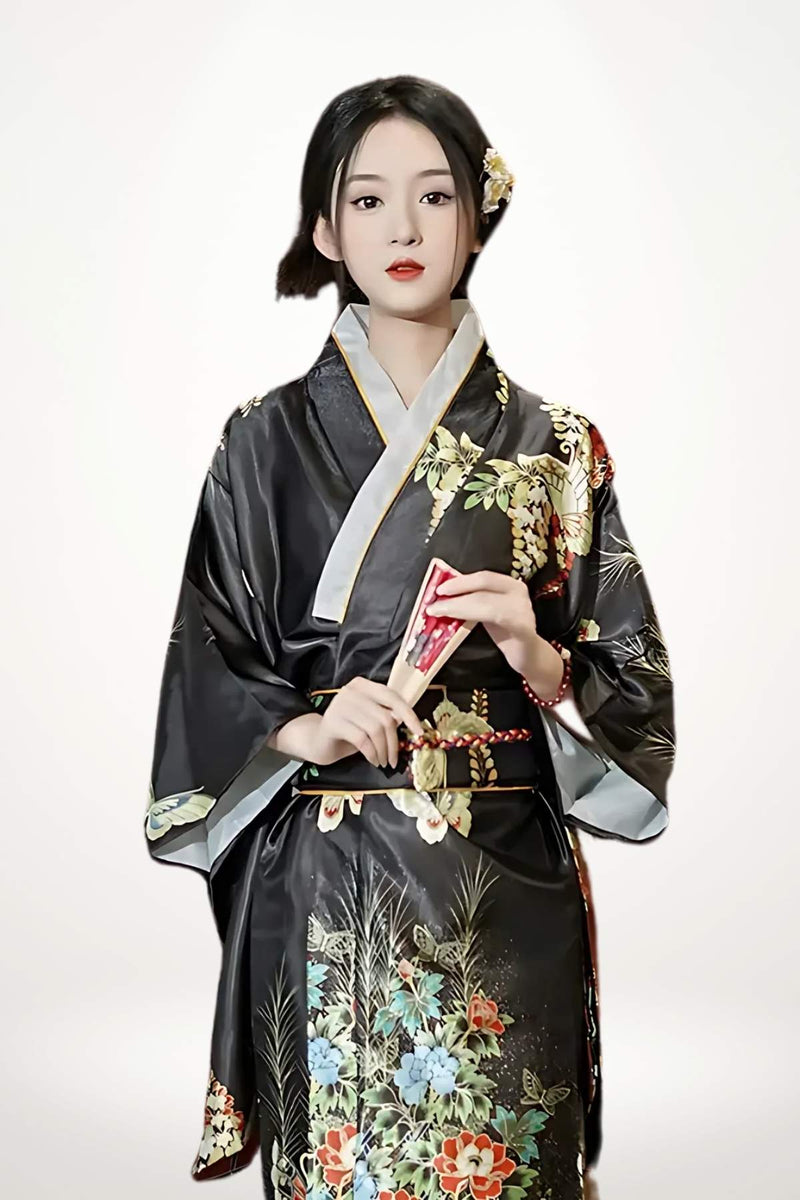 Femme en kimono noir avec motifs floraux colorés, tenant un éventail, sur fond blanc