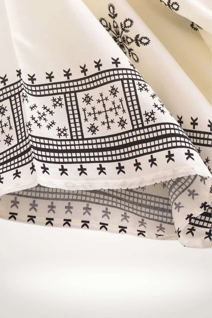 Un kimono léger aux motifs géométriques noirs sur fond blanc, évoquant un style bohème et élégant