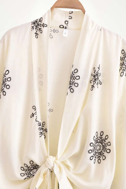 Kimono léger en tissu crème, orné de motifs floraux noirs, noué à l'avant pour un style bohème