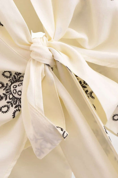 Un kimono léger en tissu crème avec des motifs noirs, noué à la taille, évoquant une élégance bohème