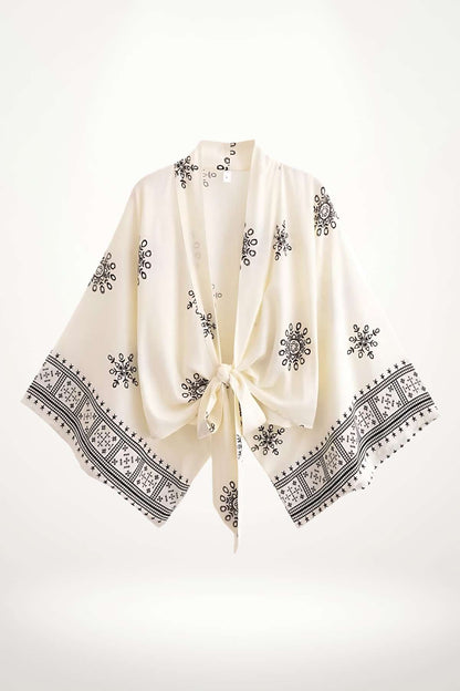 Kimono léger en tissu crème avec motifs noirs, noué à la taille, manches larges et décor élégant