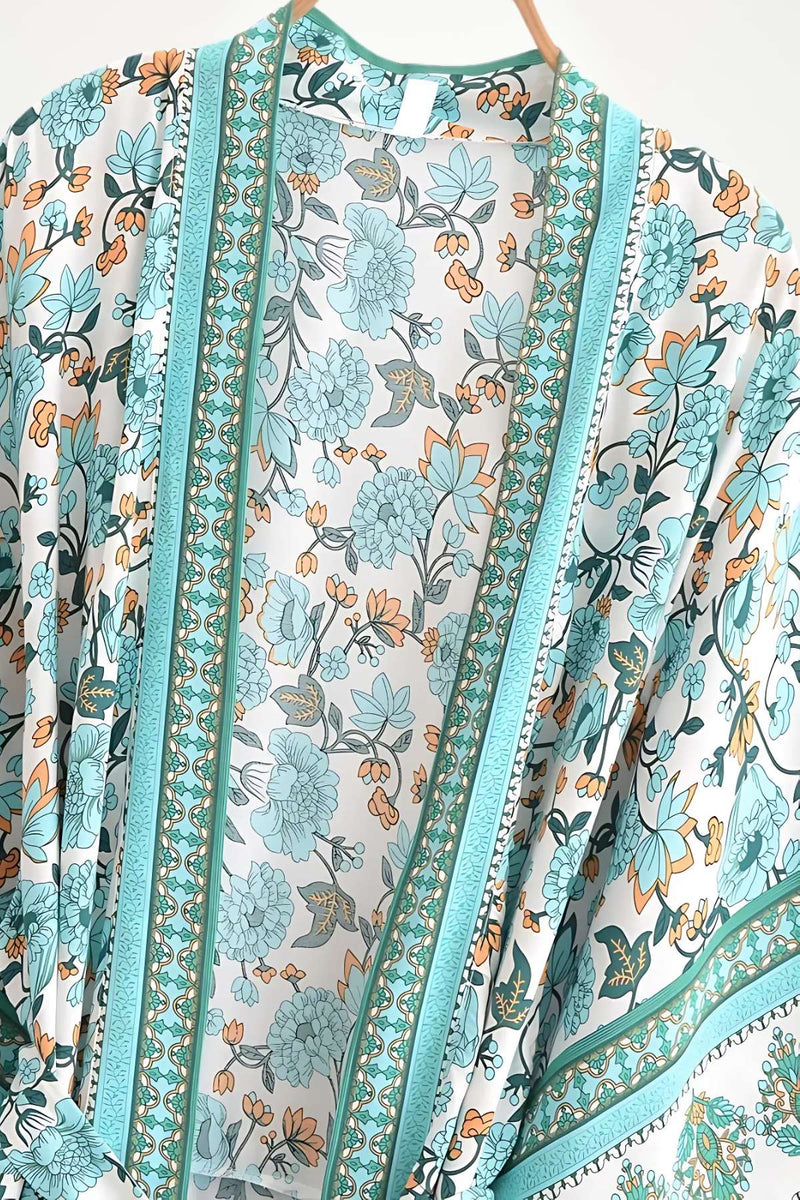 Kimono léger aux motifs floraux turquoise et orange sur fond blanc, avec des détails en dentelle délicate