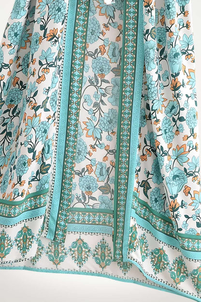 Un kimono en tissu léger, aux motifs floraux turquoise et orange, évoquant l'élégance estivale