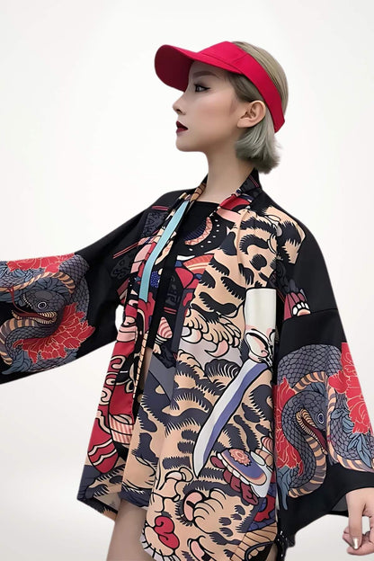 Femme en kimono noir aux motifs colorés, portant une casquette rouge, se tenant dans un décor minimaliste