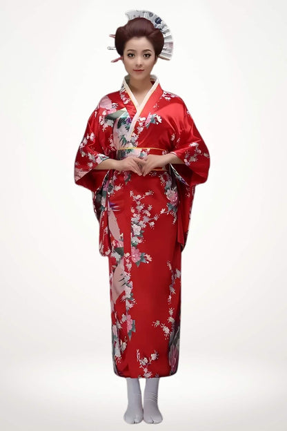Femme debout portant un kimono long rouge et blanc en satin orné de motifs floraux japonais et ceinture obi tressée.
