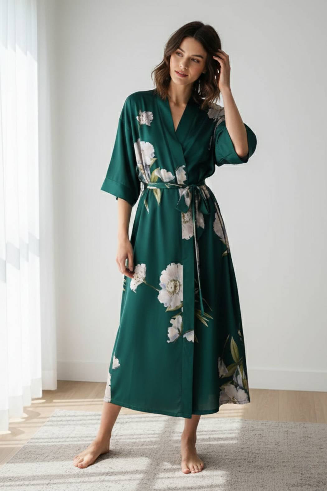 Kimono vert en satin avec des motifs floraux blancs, porté par une femme debout dans un intérieur lumineux