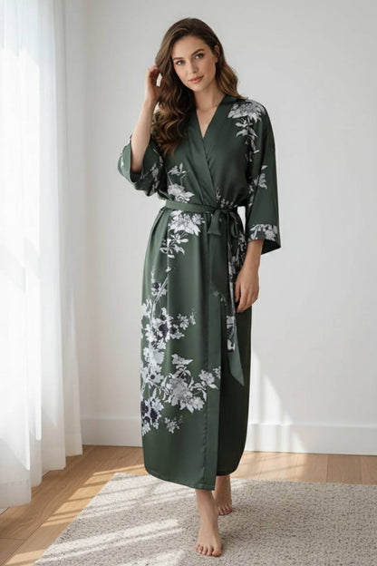 Femme en kimono vert foncé avec motifs floraux, posant dans un intérieur lumineux et moderne