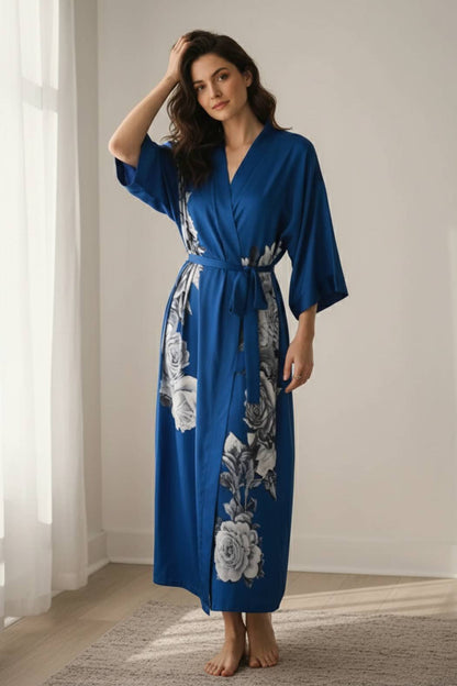 Femme posant en kimono long bleu avec motifs floraux gris, dans un décor lumineux et minimaliste