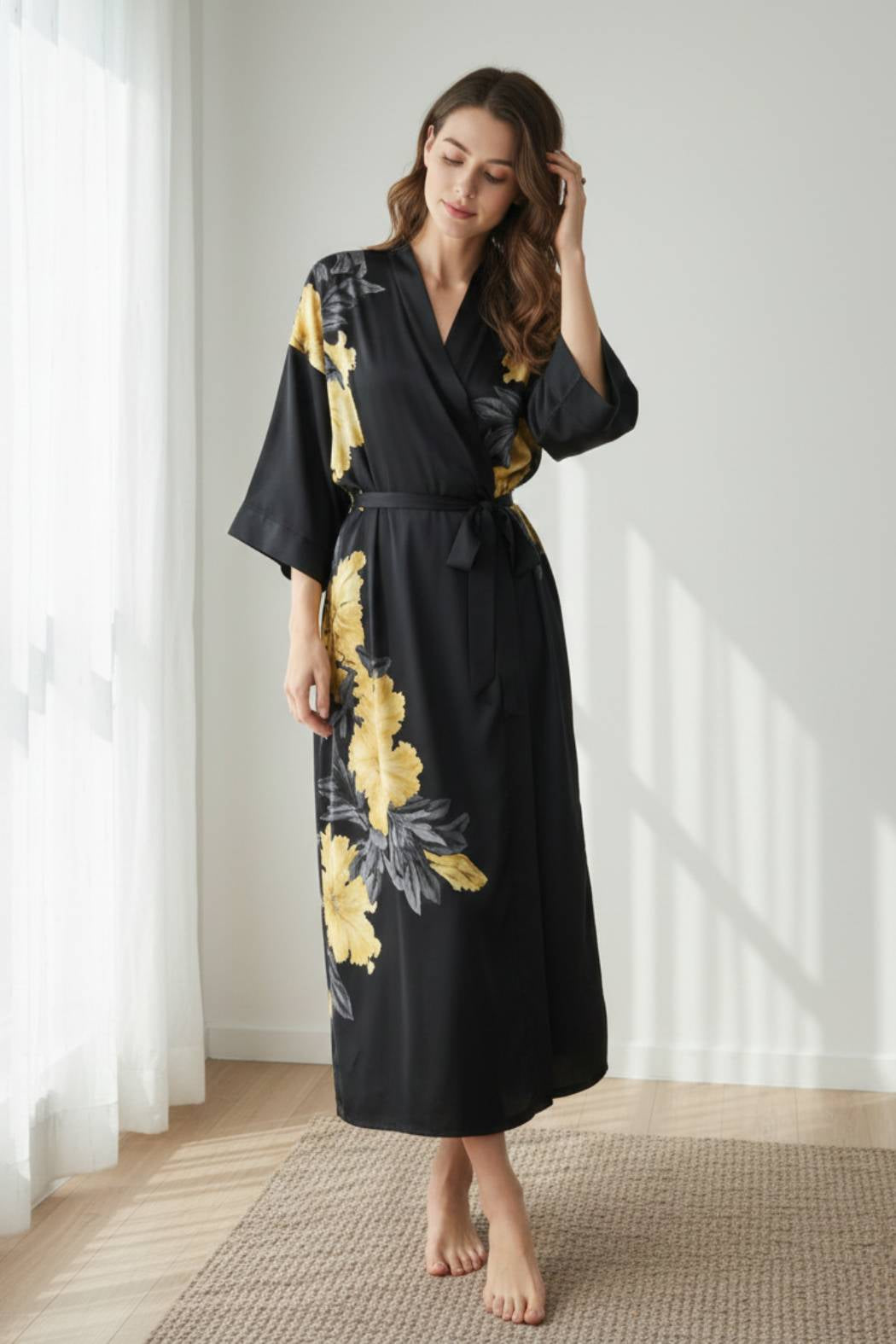 Femme en kimono noir avec motifs floraux jaunes, posant dans un intérieur lumineux et minimaliste