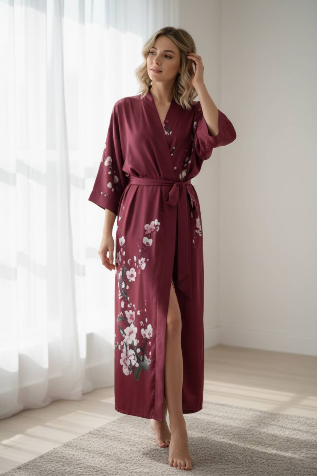 Femme en kimono rouge avec motifs floraux, posant près d'une fenêtre lumineuse sur un tapis clair