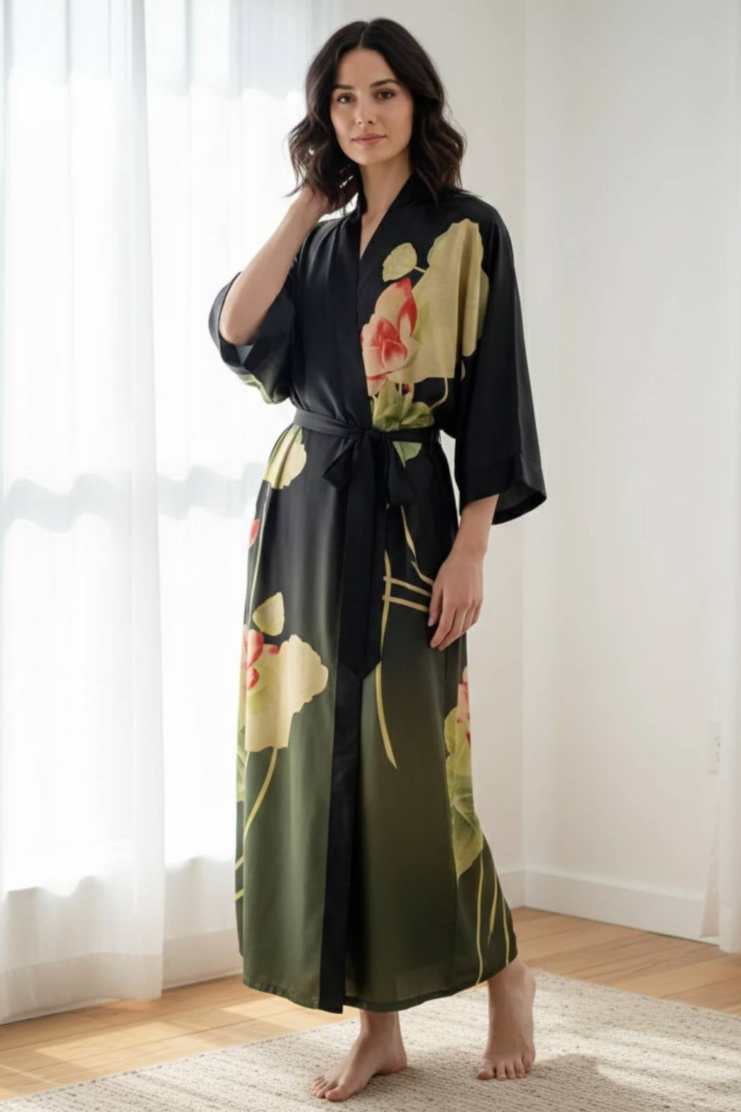 Femme portant un kimono noir avec des motifs floraux colorés, debout dans une pièce lumineuse et moderne