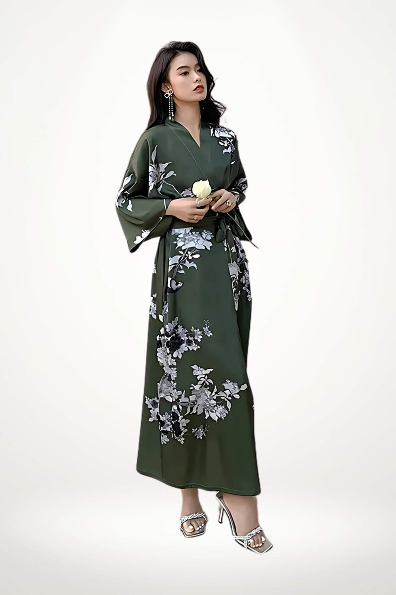 Femme en kimono vert foncé avec motifs floraux, posant élégamment avec une rose blanche dans les mains