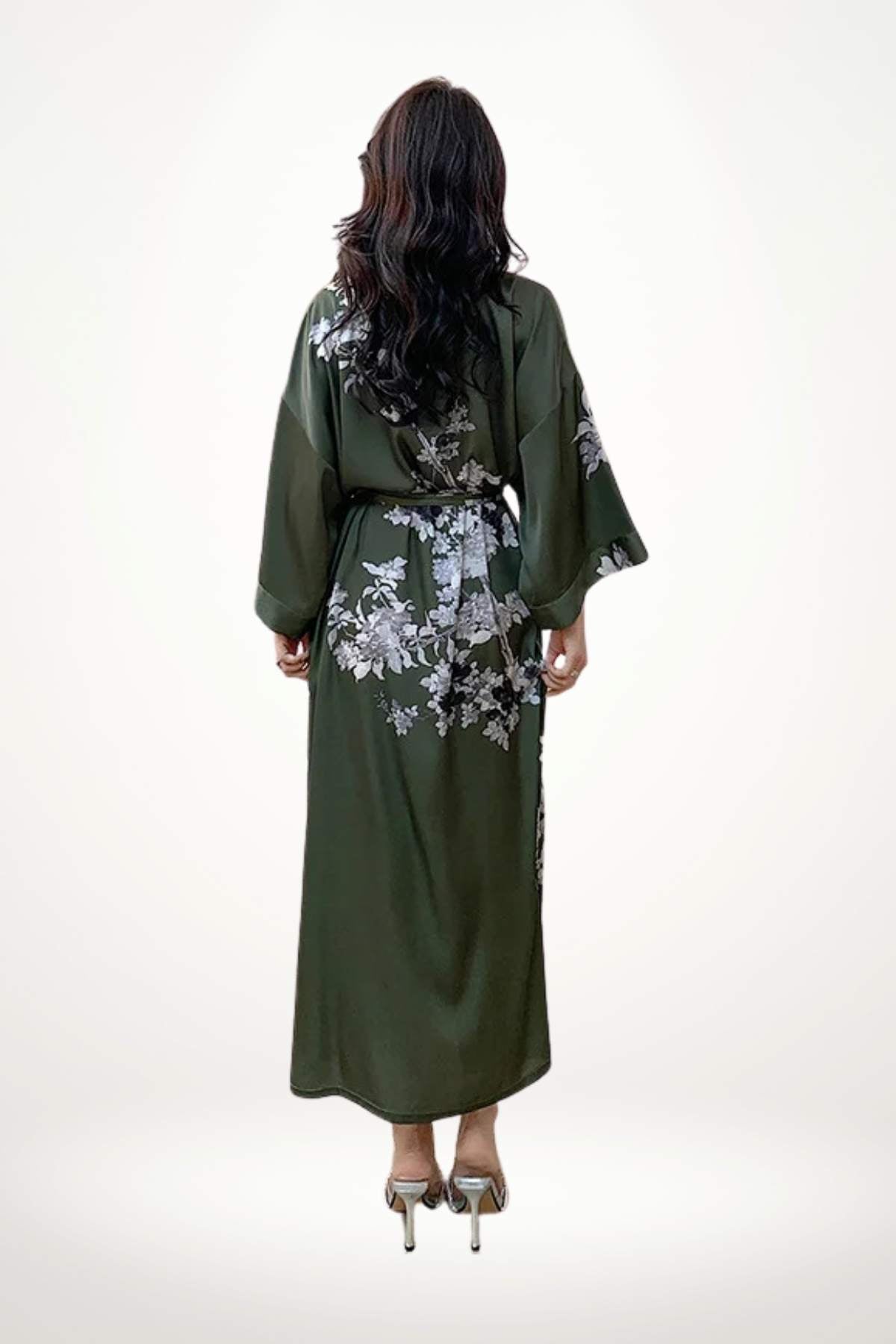 Femme de dos portant un kimono vert foncé avec des motifs floraux blancs, cheveux longs et ondulés