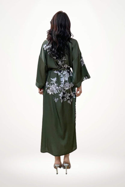 Femme de dos portant un kimono vert foncé avec des motifs floraux blancs, cheveux longs et ondulés