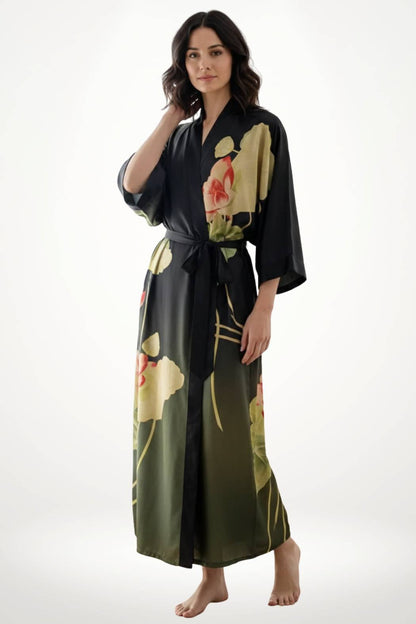 Femme en kimono noir avec motifs floraux, posant avec un sourire sur fond blanc, pieds nus et ceinture nouée