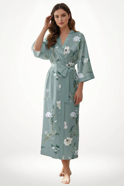 Femme en kimono léger vert avec motifs floraux, posant avec une main dans les cheveux sur fond neutre
