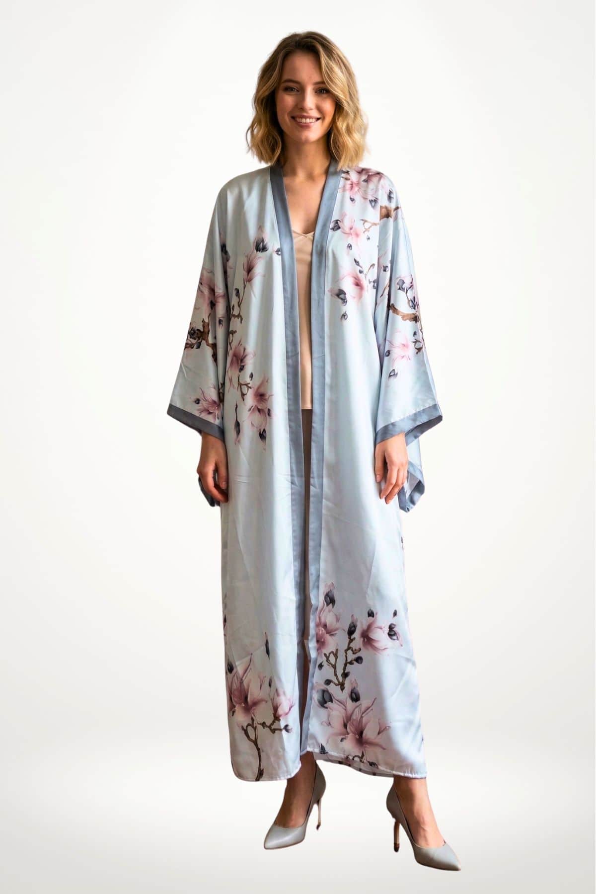 Femme souriante portant un kimono long bleu avec des motifs floraux roses sur fond clair