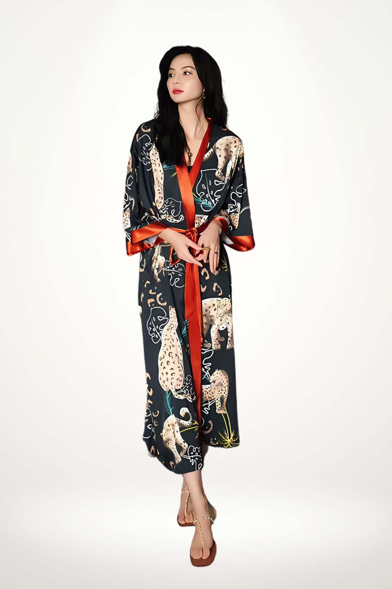 Femme en kimono noir avec motifs félins, ceinture rouge, posant sur fond clair avec une allure audacieuse