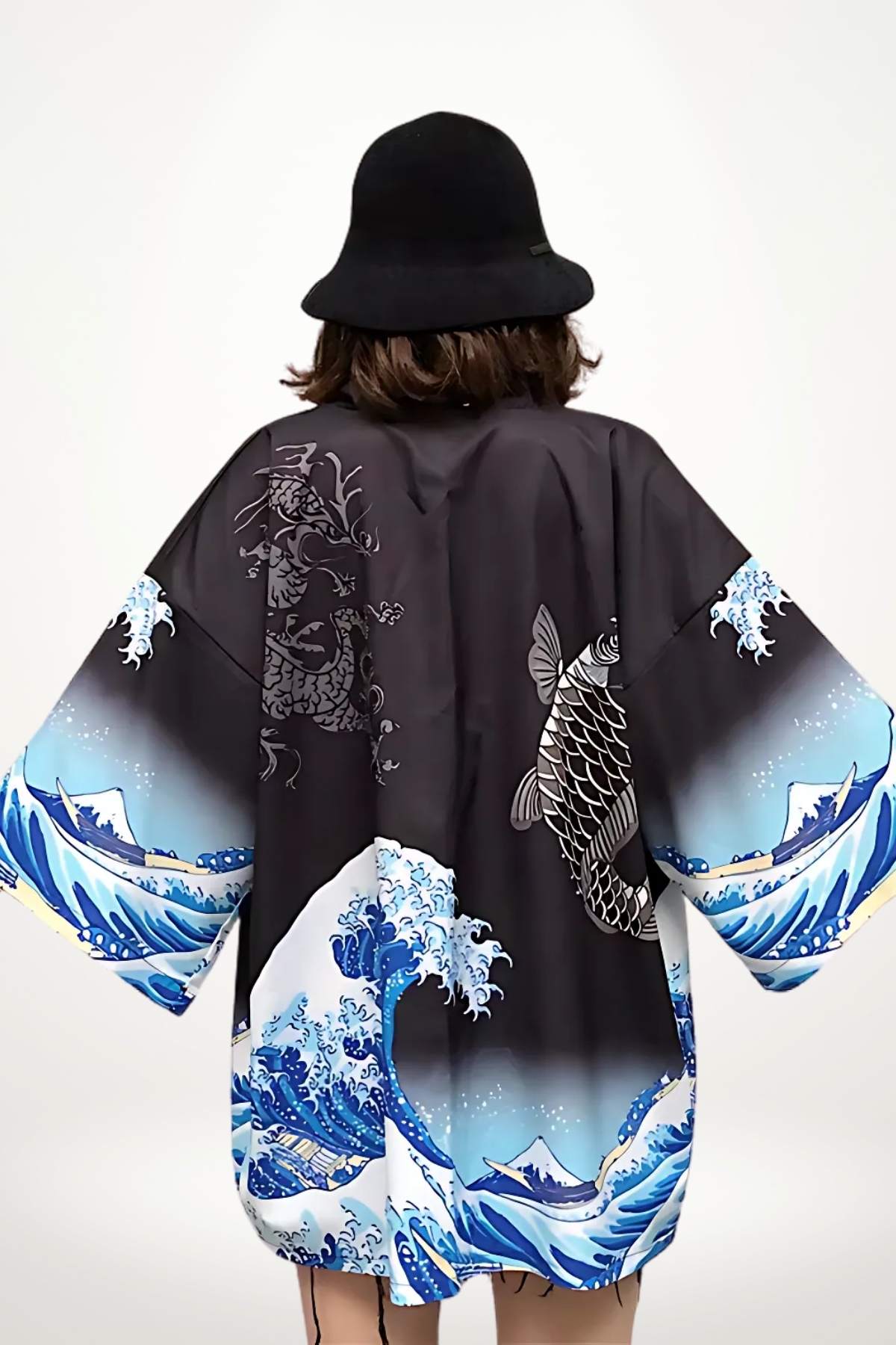 Kimono noir avec motifs de vagues et de poisson, porté par une femme au chapeau, sur fond blanc