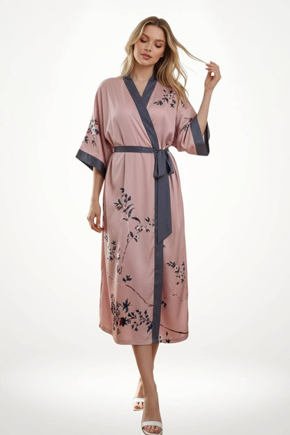 Femme en kimono rose avec motifs floraux, ceinture grise, posant élégamment sur fond blanc