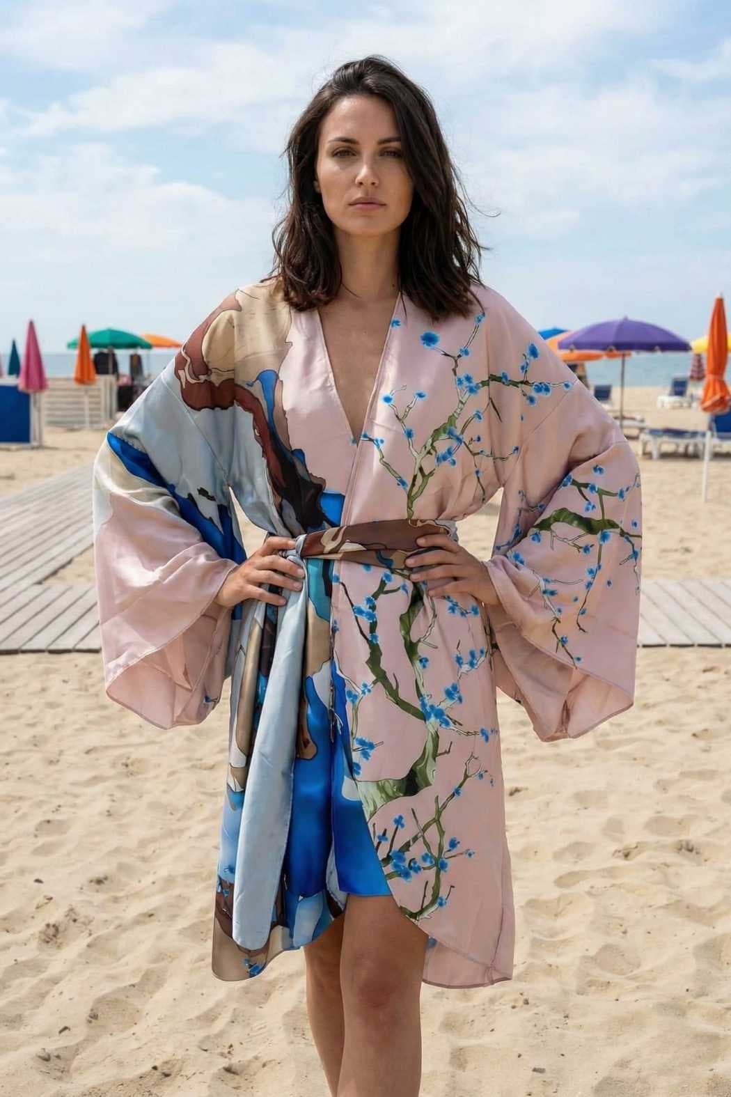 Femme portant un kimono en satin aux couleurs pastel, avec des motifs floraux, sur une plage ensoleillée