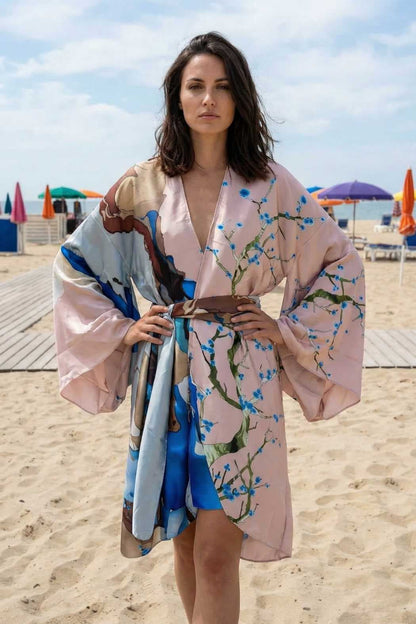 Femme portant un kimono en satin aux couleurs pastel, avec des motifs floraux, sur une plage ensoleillée