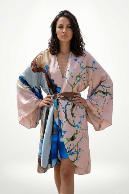 Kimono en satin aux teintes pastel, motifs floraux délicats, manches larges et ceinture assortie, posé sur fond neutre