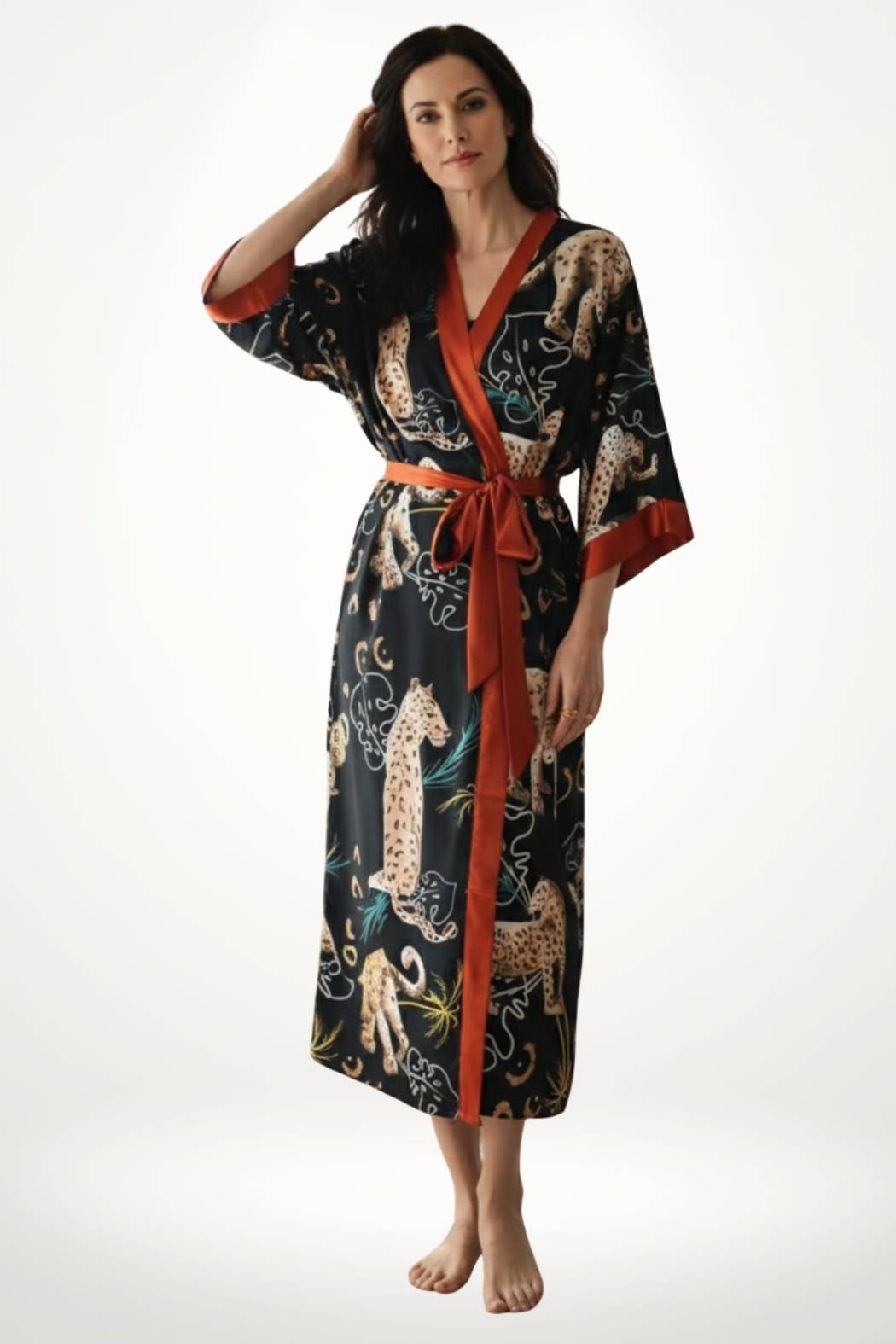 Femme portant un kimono noir avec motifs de léopards et ceinture satinée rouge, posant sur un fond clair