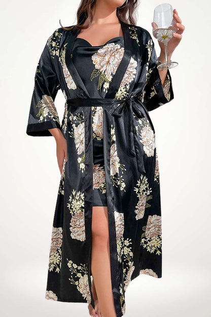 Femme en kimono noir satiné avec des motifs floraux, tenant un verre, dans une posture élégante et douce