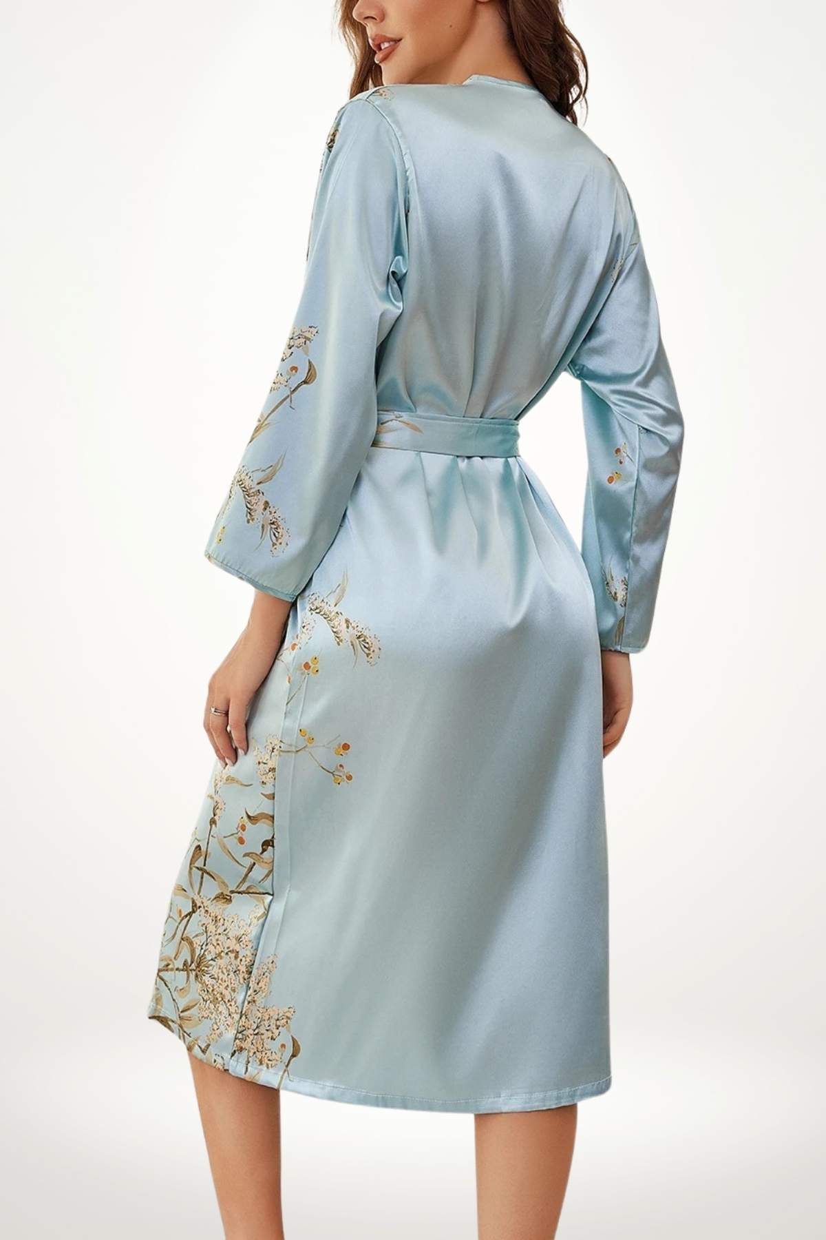 Kimono en satin bleu clair avec des motifs floraux dorés, ceinturé à la taille, dans un décor minimaliste